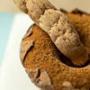 An orange mushroom rests upside-down with its smooth, dented stalk pointing upward. A few triangular pieces of the top of the cap hug the underside which has a rough, felted texture